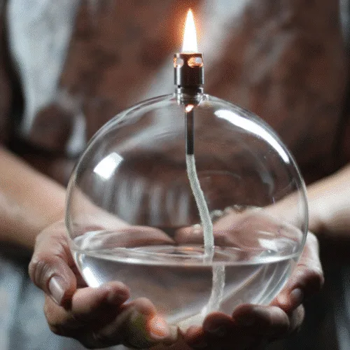 Lampe à huile ronde en verre modèle Classique tenu entre les mains d'une femme
