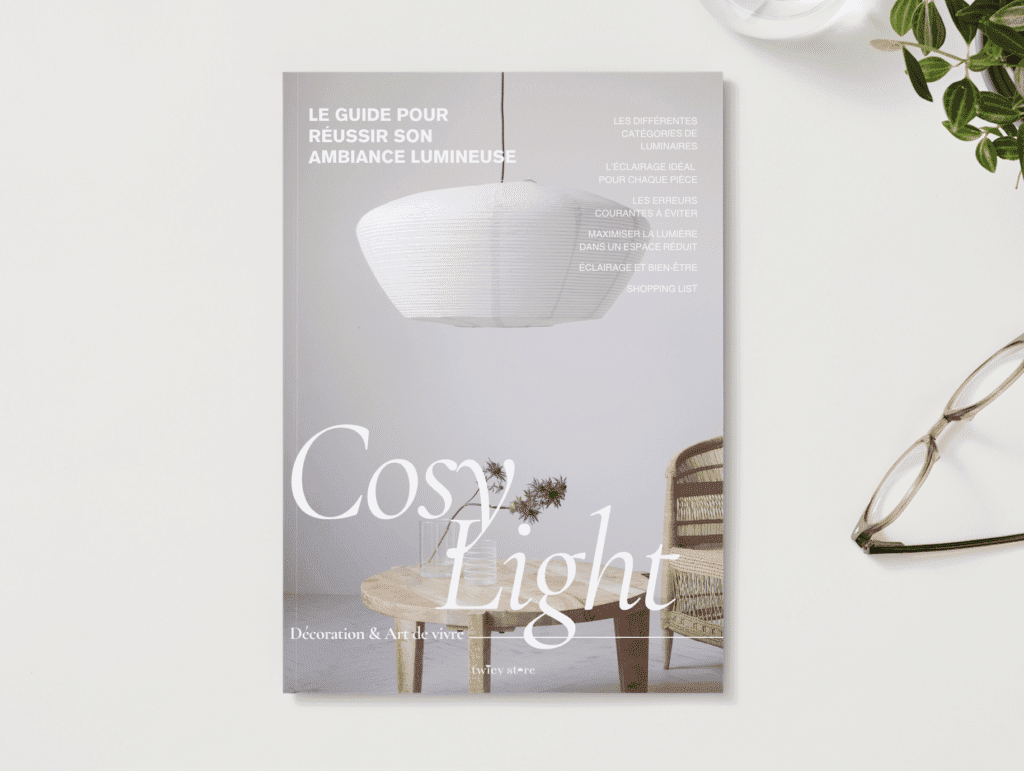 Cosy Light guide gratuit à télécharger pour réussir son ambiance lumineuse édité par Twicy Store posé sur un bureau avec des lunettes et une plante verte