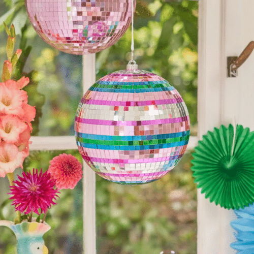 Photo d'une boule à facettes à rayures multicolores suspendue devant une fenêtre