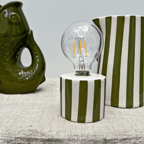 Lampe sans fil à rayures kaki lumière nomade - Twicy Store disposée sur une table devant à pichet à rayure et un vase