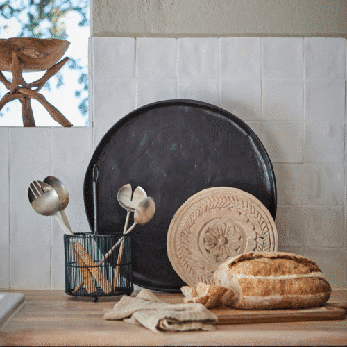 Plateau rond sur pieds en bois sculpté "Treasure" - Twicy Store disposé contre le mur d'une cuisine