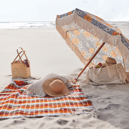 Couverture de pique-nique "Solveig" - Twicy Store posée sur le sable avec un parasol et un nécessaire de picnic