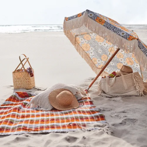 Couverture de pique-nique "Solveig" - Twicy Store posée sur le sable avec un parasol et un nécessaire de picnic