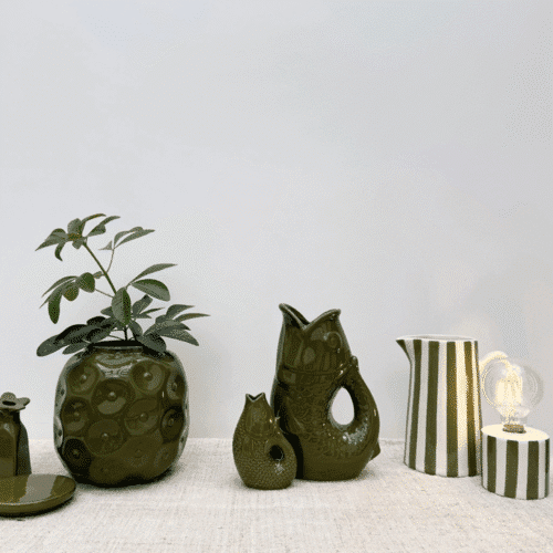 Lampe sans fil à rayures kaki lumière nomade - Twicy Store disposée sur une table devant à pichet à rayure et un vase
