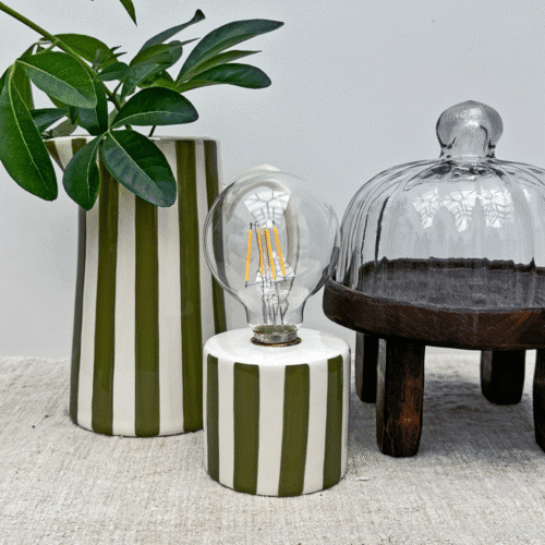 Lampe sans fil à rayures kaki lumière nomade - Twicy Store disposée sur une table devant à pichet à rayure et un vase
