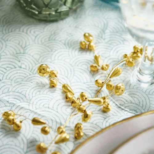 Guirlande de petites clochettes - Twicy Store disposée au centre d'une table de repas sur une nappe à motifs verts