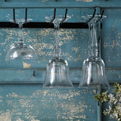 Support de verres à pieds en métal noir mat - Twicy Store contre un mur bleu avec 3 verres suspendus